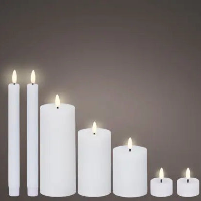 Set of white candles of various sizes with a dimly lit background