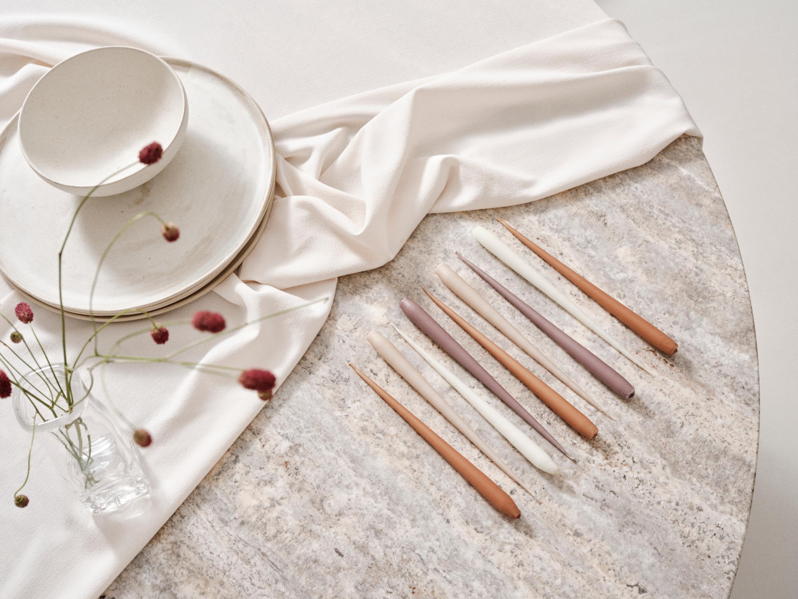 Four slim metallic rose gold taper candles standing upright in a row against a plain white background.